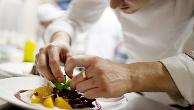 Chef in restaurant kitchen cooking, only hands to be se