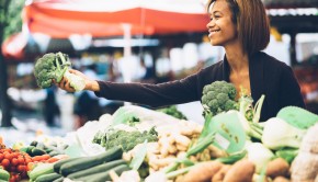 Young woman buying vegetables at farmers market