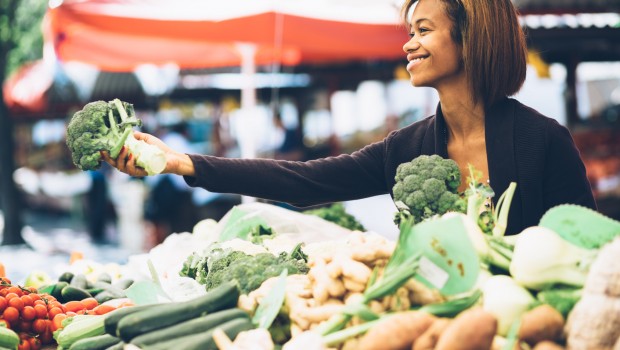 Young woman buying vegetables at farmers market